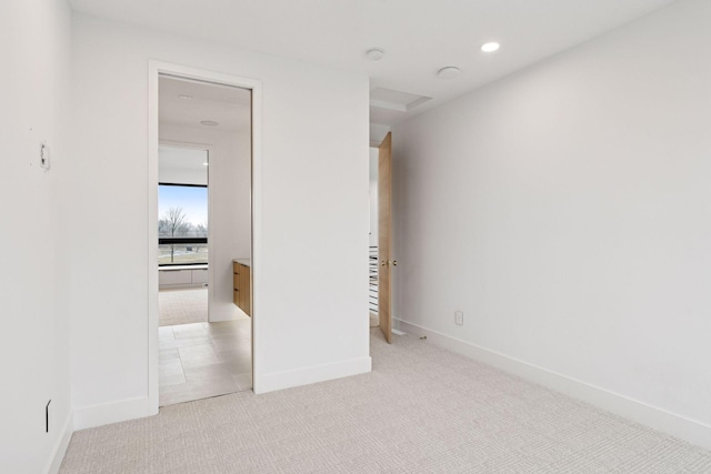 unfurnished bedroom with baseboards, recessed lighting, ensuite bath, and light colored carpet