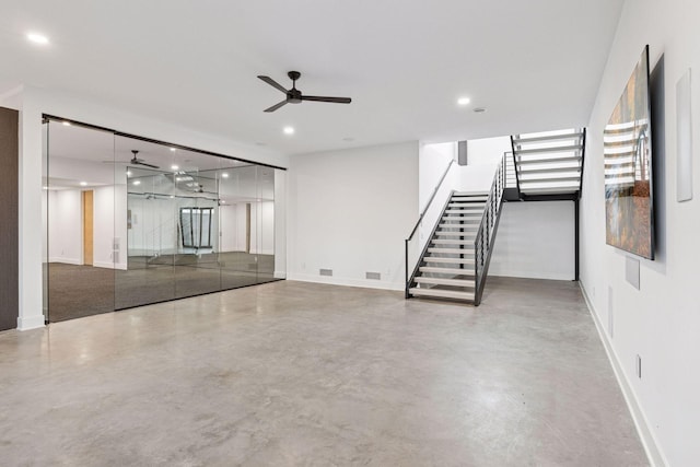 spare room with finished concrete floors, stairway, and recessed lighting