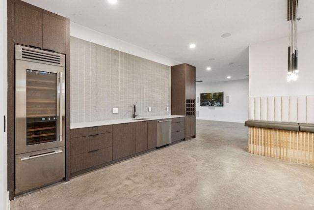 kitchen featuring recessed lighting, light countertops, stainless steel dishwasher, modern cabinets, and concrete floors