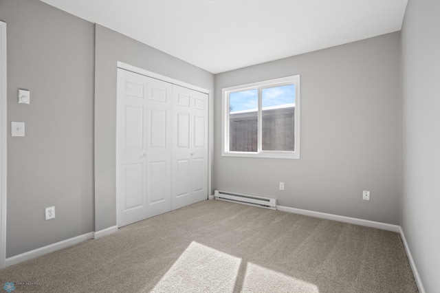 unfurnished bedroom with carpet, a closet, and baseboard heating