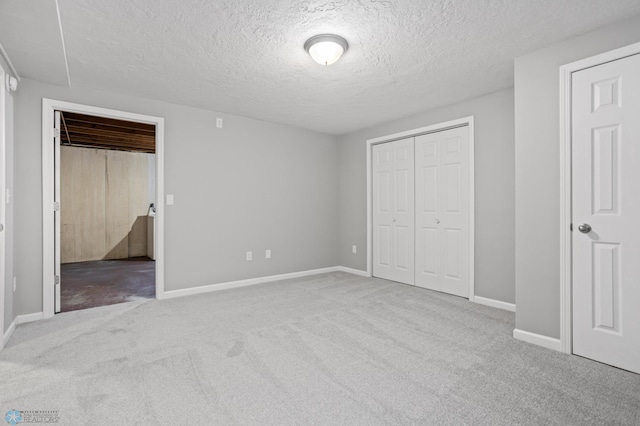 unfurnished bedroom with light carpet, a closet, and a textured ceiling