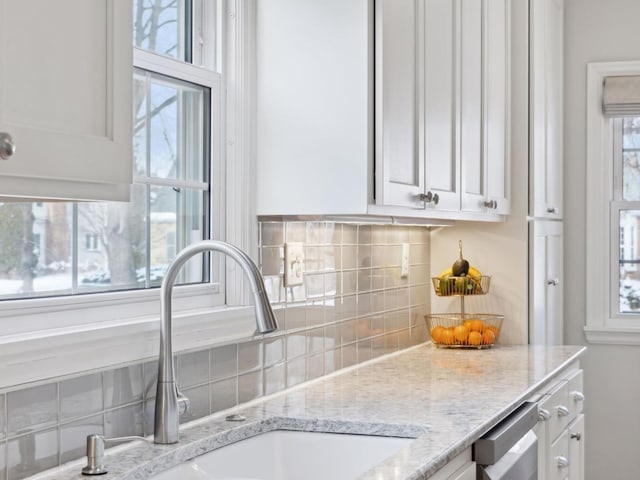 kitchen with white cabinetry, light stone countertops, decorative backsplash, and a sink