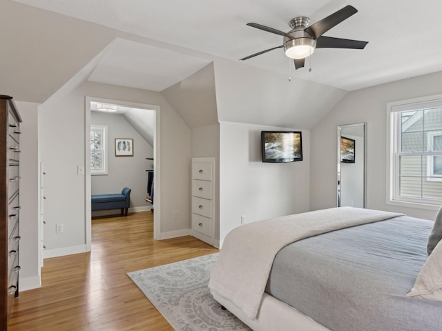 bedroom with vaulted ceiling, a ceiling fan, baseboards, and light wood-style floors