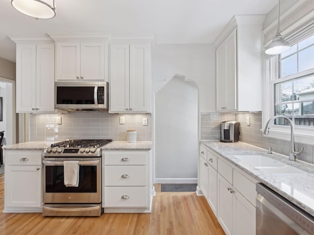 kitchen featuring stainless steel appliances, white cabinetry, pendant lighting, and a sink