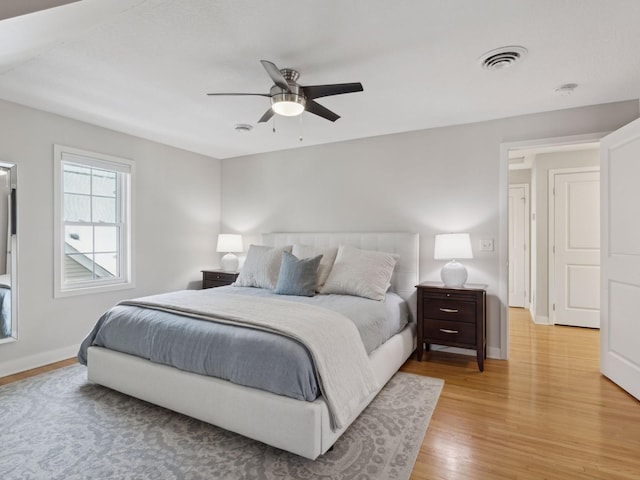 bedroom featuring baseboards, visible vents, a ceiling fan, and light wood finished floors