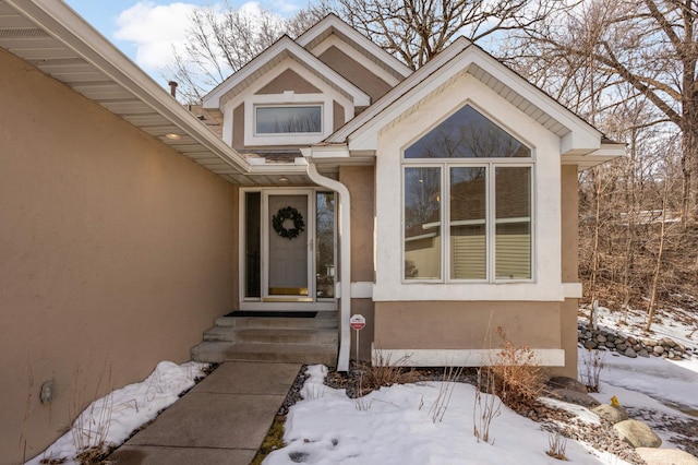 snow covered property entrance featuring stucco siding