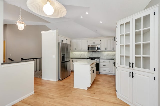 kitchen with a center island, appliances with stainless steel finishes, light wood finished floors, decorative backsplash, and vaulted ceiling