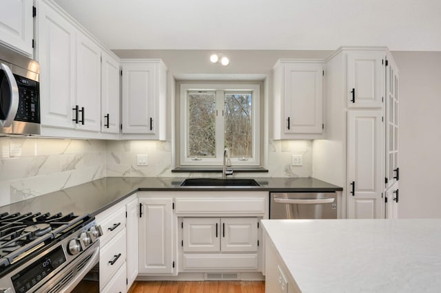 kitchen featuring visible vents, white cabinets, stainless steel appliances, and a sink