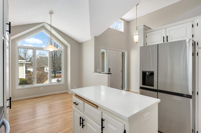 kitchen featuring light wood-type flooring, vaulted ceiling, stainless steel refrigerator with ice dispenser, and white cabinetry