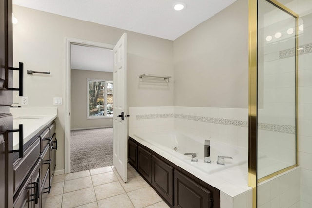 full bath featuring tile patterned floors, baseboards, a jetted tub, and vanity