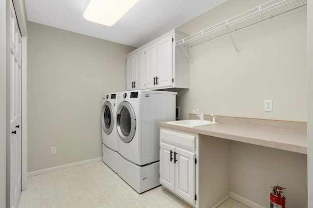 laundry room with light floors, baseboards, washing machine and clothes dryer, cabinet space, and a sink