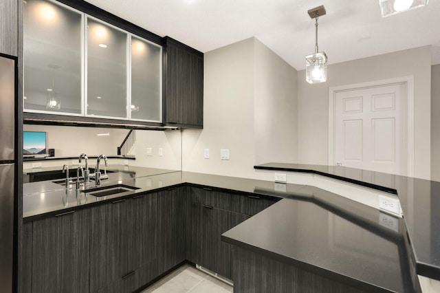 kitchen with dark countertops, decorative light fixtures, a peninsula, modern cabinets, and a sink