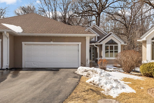 single story home featuring a shingled roof, a garage, driveway, and stucco siding