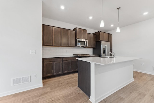 kitchen with visible vents, a sink, dark brown cabinetry, appliances with stainless steel finishes, and backsplash