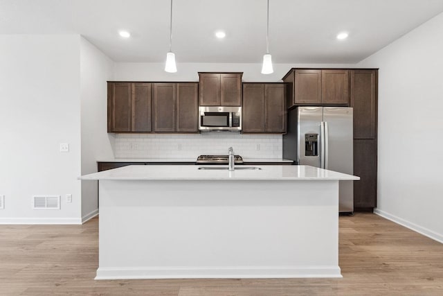 kitchen featuring dark brown cabinetry, a center island with sink, appliances with stainless steel finishes, and a sink