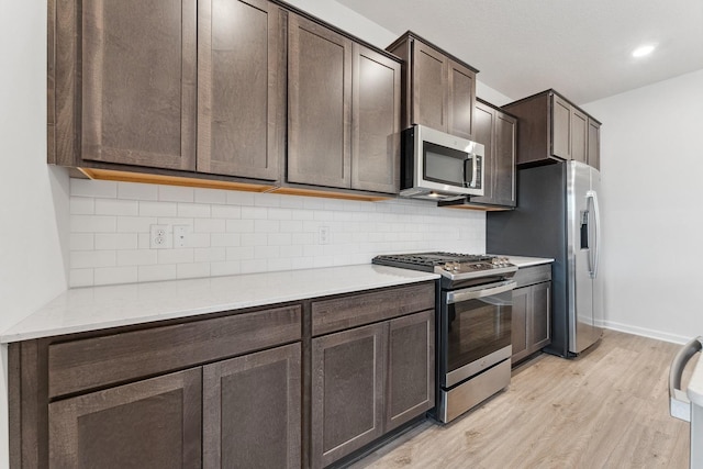 kitchen featuring light wood-type flooring, stainless steel appliances, dark brown cabinetry, and light countertops