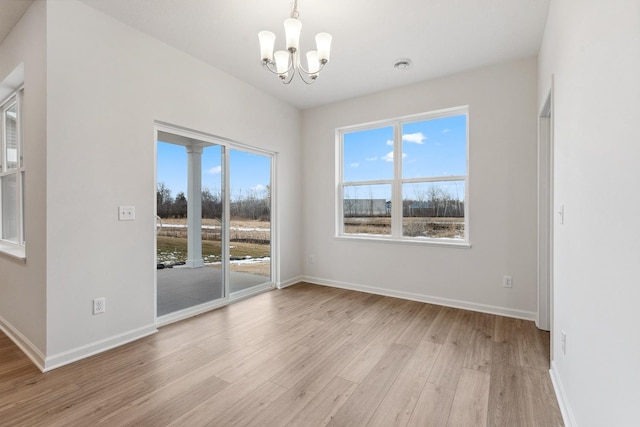 unfurnished dining area featuring baseboards, a notable chandelier, and light wood-style flooring