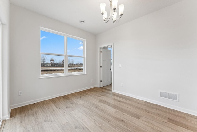 spare room featuring visible vents, baseboards, a notable chandelier, and light wood finished floors