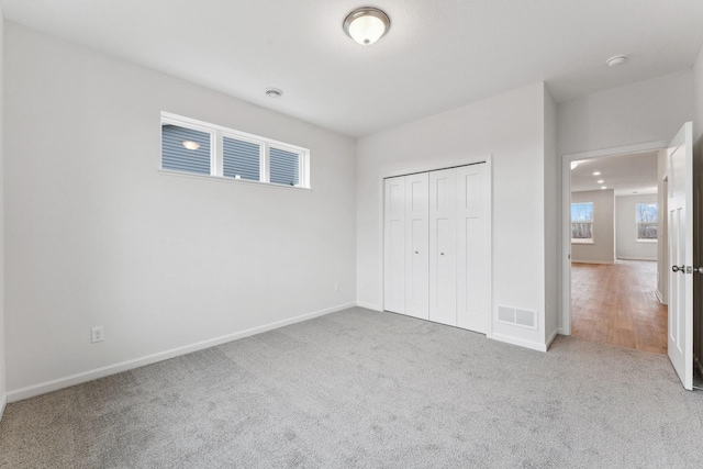 unfurnished bedroom featuring carpet flooring, baseboards, visible vents, and a closet