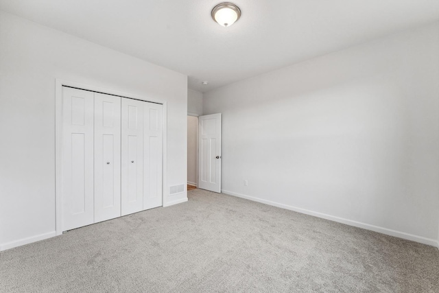 unfurnished bedroom featuring visible vents, carpet, baseboards, and a closet