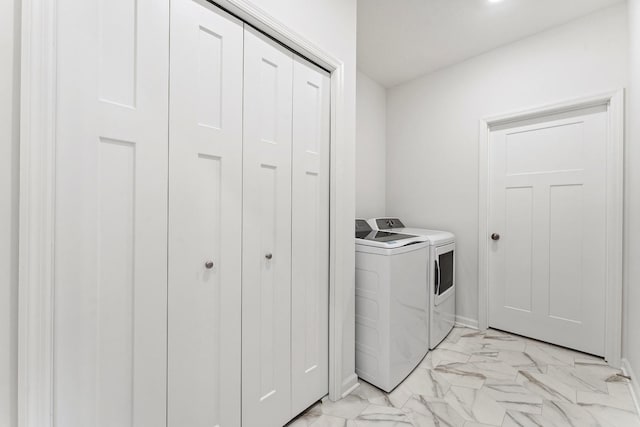 washroom featuring laundry area, washing machine and dryer, marble finish floor, and baseboards