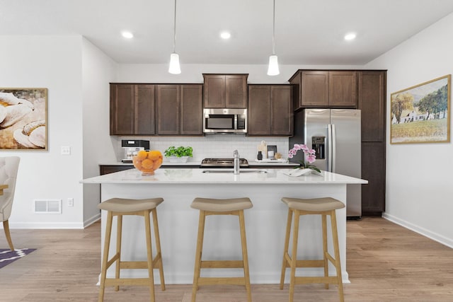 kitchen featuring a breakfast bar, tasteful backsplash, appliances with stainless steel finishes, and a sink