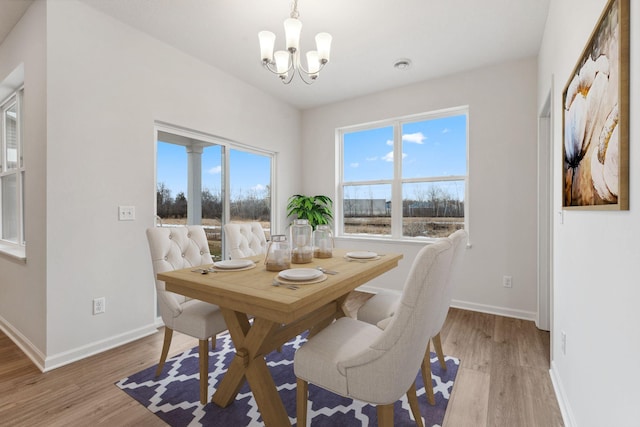 dining room with a chandelier, baseboards, and light wood-style floors