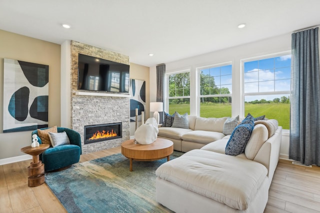 living room with a stone fireplace and light hardwood / wood-style floors