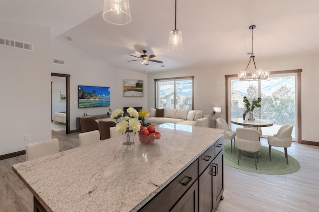 kitchen featuring light stone counters, lofted ceiling, light hardwood / wood-style floors, and hanging light fixtures