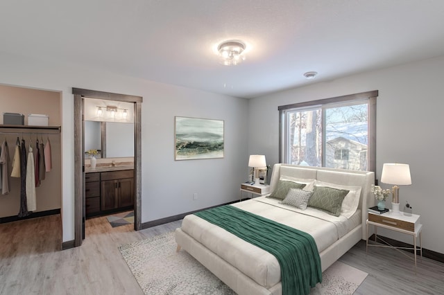 bedroom featuring sink, light hardwood / wood-style flooring, ensuite bathroom, a spacious closet, and a closet