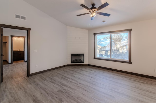 unfurnished living room featuring ceiling fan, a large fireplace, lofted ceiling, and light hardwood / wood-style flooring