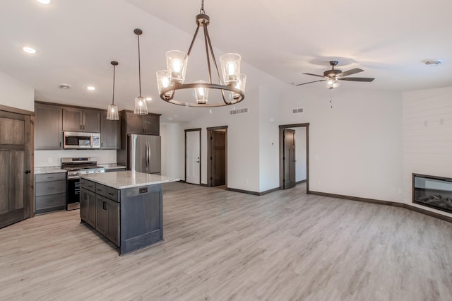 kitchen featuring dark brown cabinetry, a center island, vaulted ceiling, hanging light fixtures, and appliances with stainless steel finishes