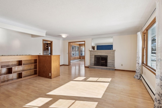 unfurnished living room featuring baseboard heating, a stone fireplace, and light hardwood / wood-style floors