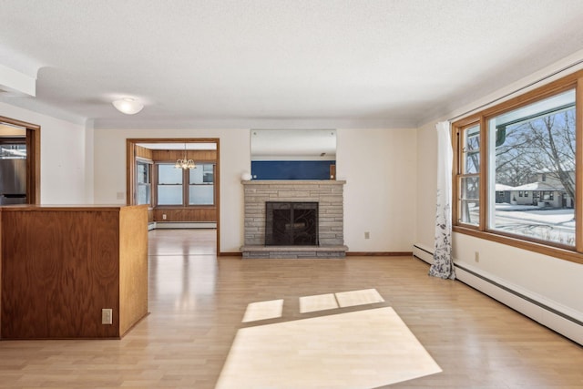 unfurnished living room with a baseboard heating unit, a stone fireplace, light hardwood / wood-style flooring, and a textured ceiling