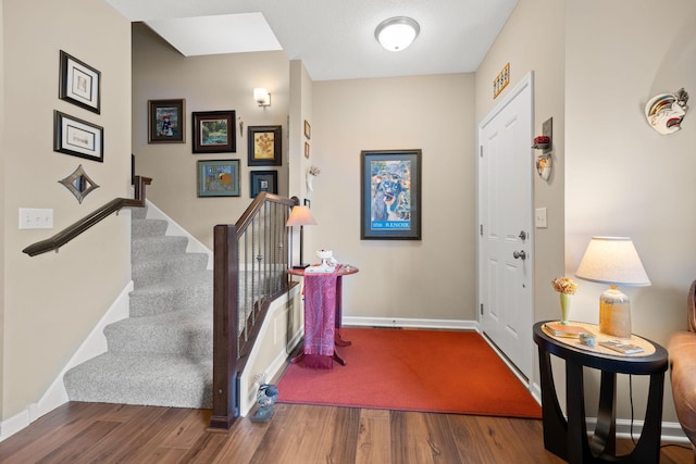 foyer featuring stairs, baseboards, and wood finished floors