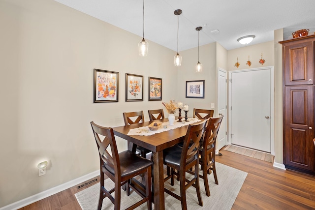 dining room featuring visible vents, baseboards, and wood finished floors