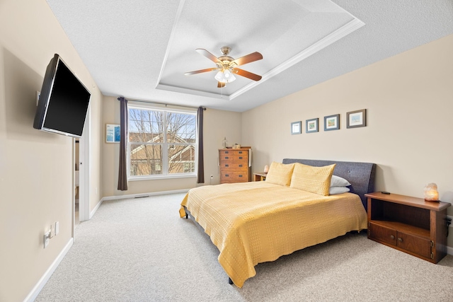 carpeted bedroom featuring ceiling fan, a tray ceiling, baseboards, and a textured ceiling