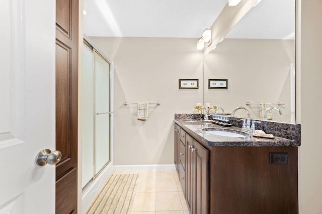 bathroom featuring tile patterned flooring, double vanity, a shower with shower door, and a sink