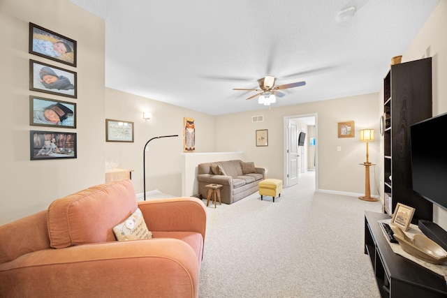 carpeted living area featuring visible vents, baseboards, a textured ceiling, and a ceiling fan