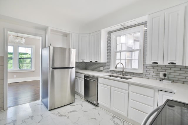 kitchen with sink, appliances with stainless steel finishes, white cabinets, pendant lighting, and backsplash