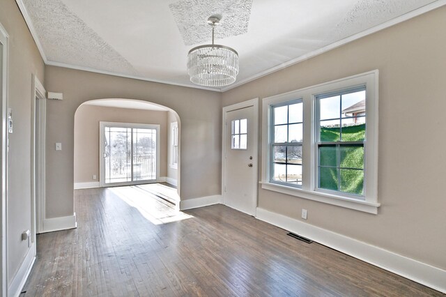entryway featuring visible vents, arched walkways, ornamental molding, dark wood-style flooring, and a notable chandelier