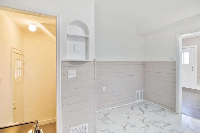 clothes washing area featuring built in shelves, marble finish floor, visible vents, and wainscoting