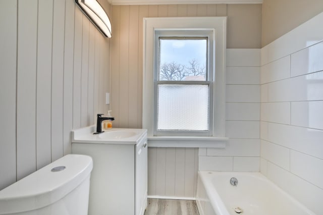 full bath with toilet, a tub, wood finished floors, and vanity