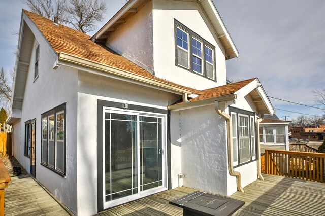 back of house with stucco siding and a wooden deck