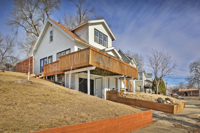 exterior space featuring a deck, an attached garage, and stucco siding