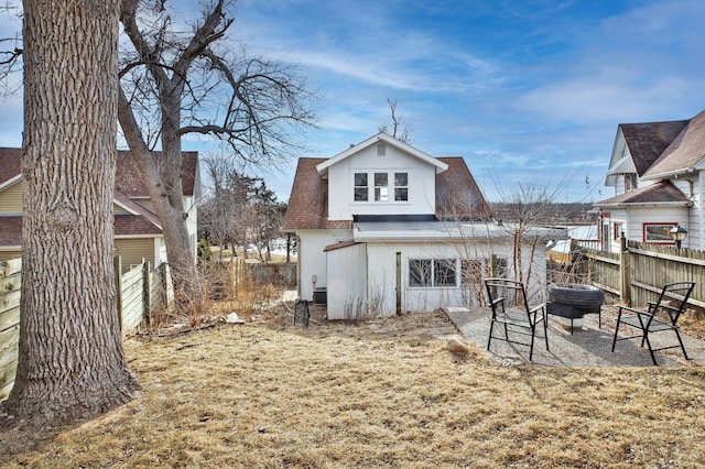 back of house featuring an outdoor fire pit, roof with shingles, fence, and central AC