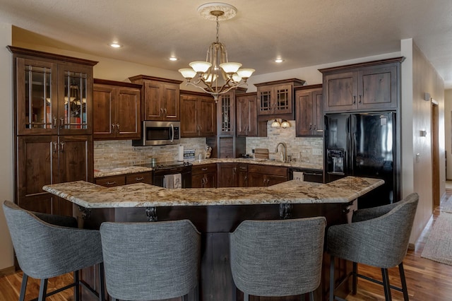 kitchen with hardwood / wood-style flooring, a large island, sink, and black appliances