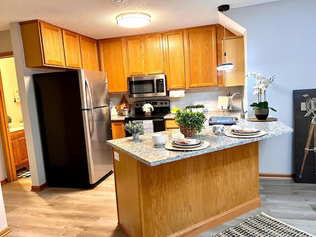 kitchen featuring sink, appliances with stainless steel finishes, light stone counters, and light hardwood / wood-style flooring