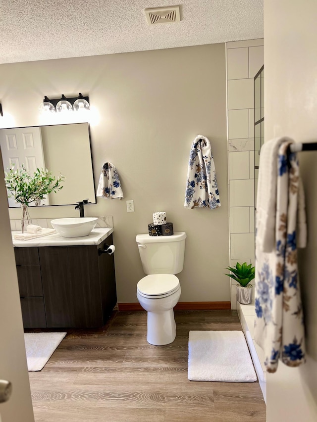 bathroom with hardwood / wood-style floors, toilet, a textured ceiling, and vanity