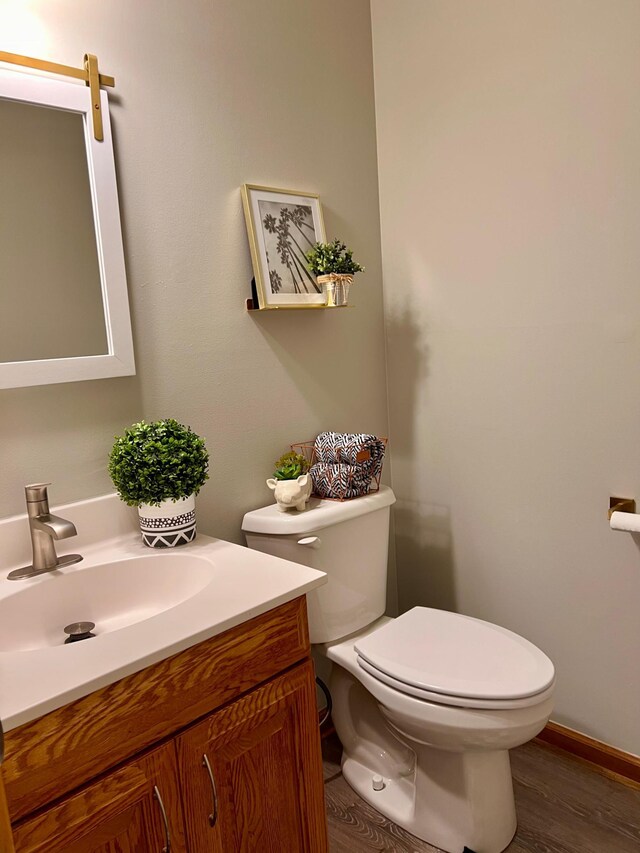 bathroom with toilet, wood-type flooring, and vanity